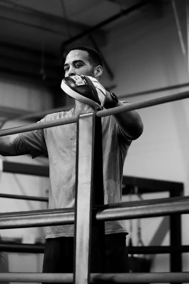 Jeremiah leaning on the ropes with a mitt in hand